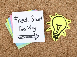Bulletin board with sticky note that reads "Fresh start this way"